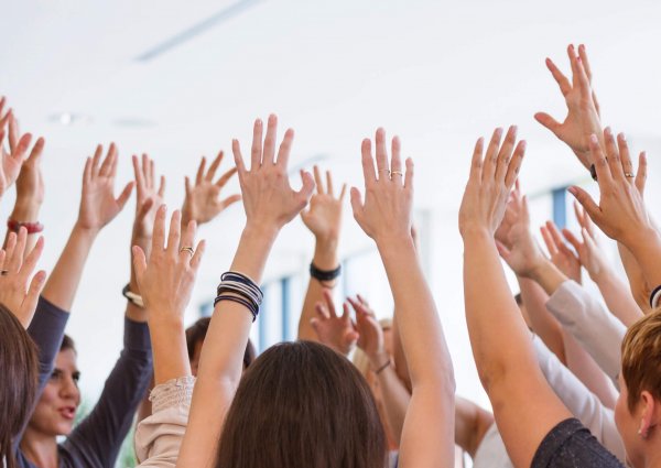 Group of women attending a training, playing together with team building games. Close up of raised hands.